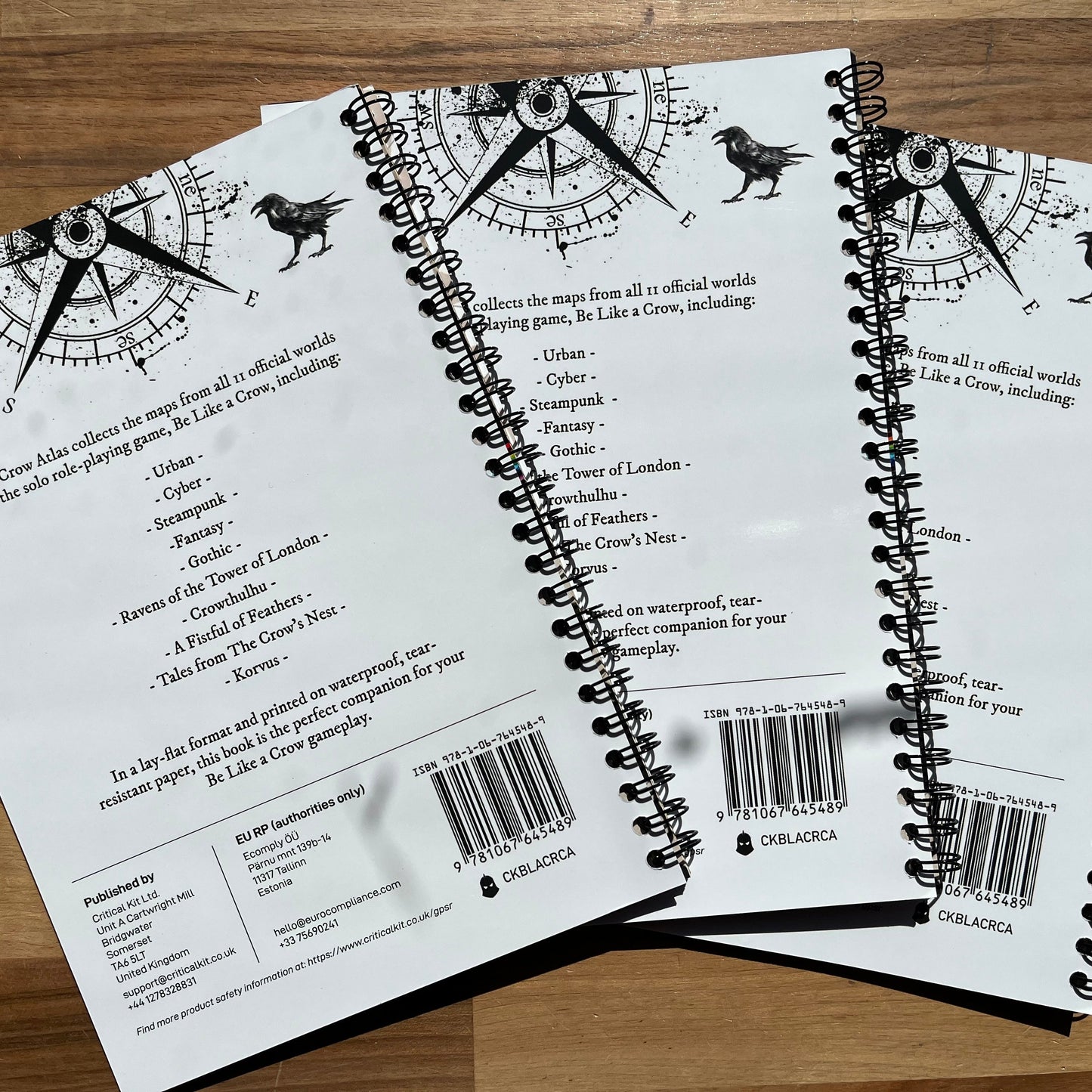Three spiral-bound books with black text and barcodes on a wooden surface