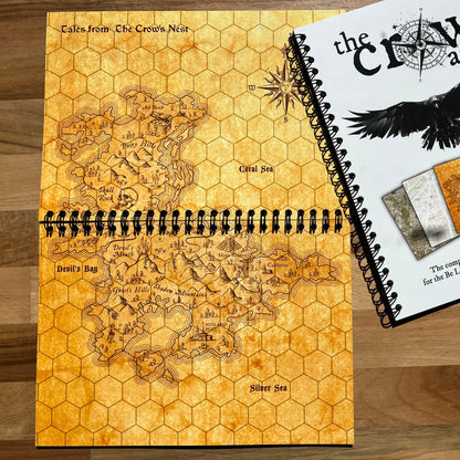 Map book with hexagonal grid design and 'The Crow Atlas' cover on a wooden surface