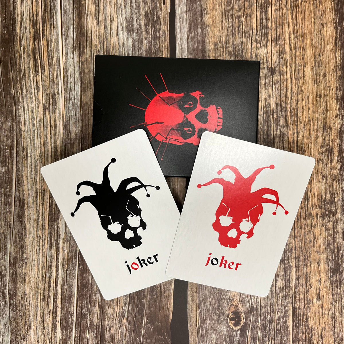 Two joker playing cards showing skeleton jesters on red and the other black
